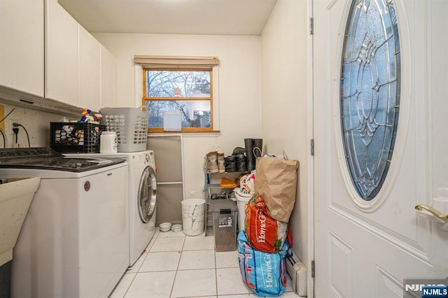 clothes washing area featuring cabinets, separate washer and dryer, and light tile patterned floors