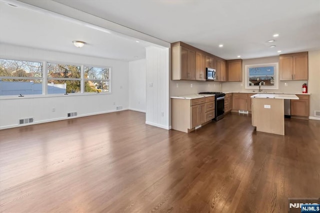 kitchen with appliances with stainless steel finishes, a center island, sink, and dark hardwood / wood-style floors