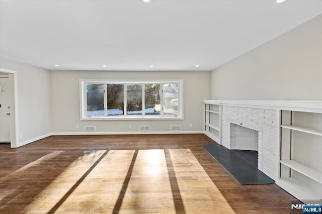 unfurnished living room with a brick fireplace and dark hardwood / wood-style floors