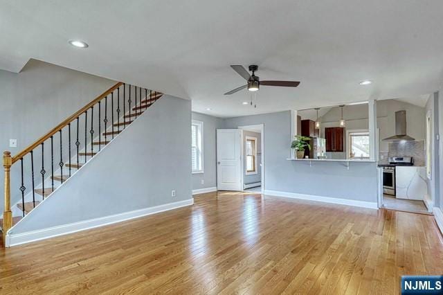 unfurnished living room with ceiling fan, a healthy amount of sunlight, and light wood-type flooring