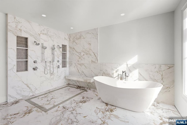 full bath with stone wall, recessed lighting, a freestanding bath, marble finish floor, and a marble finish shower