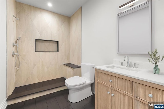 full bath featuring toilet, tile patterned floors, a tile shower, and vanity