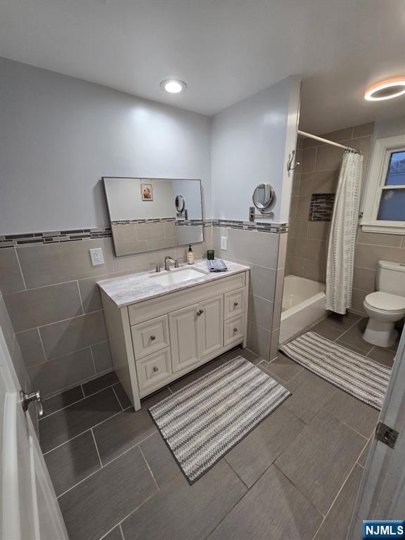 bathroom featuring tile walls, vanity, a shower with curtain, and toilet