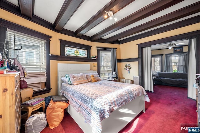 carpeted bedroom with multiple windows and beamed ceiling