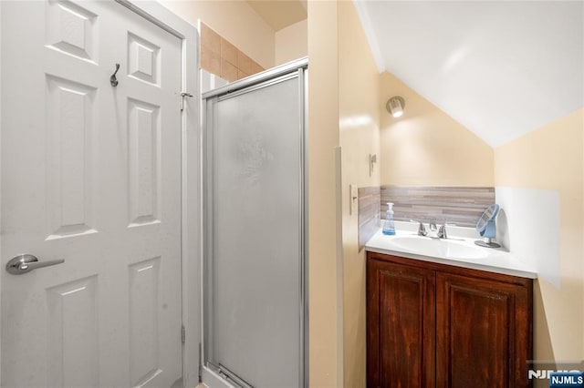 bathroom with lofted ceiling, a shower with door, and sink