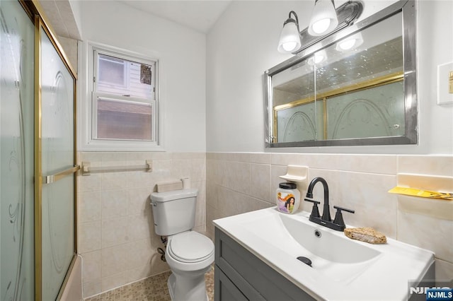 bathroom with vanity, tile walls, and toilet