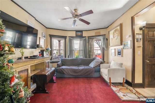 carpeted living room with ornamental molding, plenty of natural light, and ceiling fan