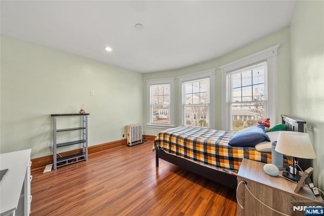 bedroom featuring multiple windows, radiator, and hardwood / wood-style flooring