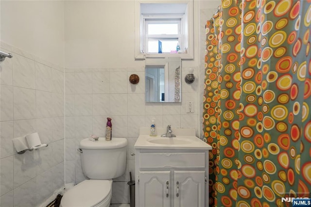 bathroom featuring vanity, toilet, and tile walls