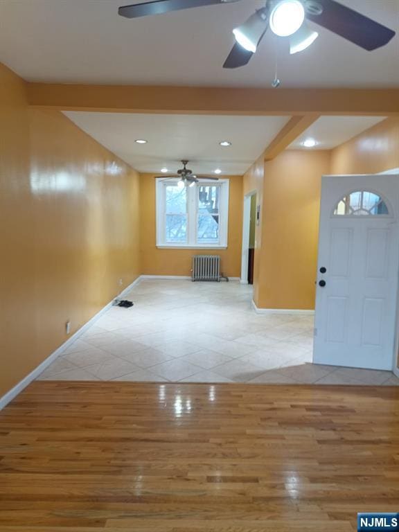 unfurnished living room with radiator, light tile patterned floors, and ceiling fan