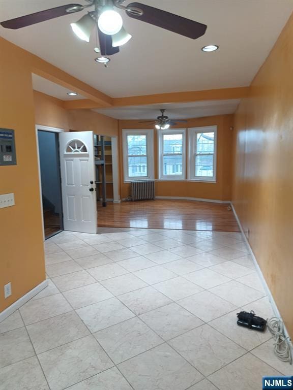 foyer with radiator heating unit, ceiling fan, and light tile patterned floors