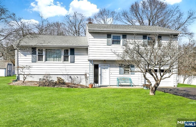 split level home featuring a garage, driveway, a front lawn, and a shingled roof