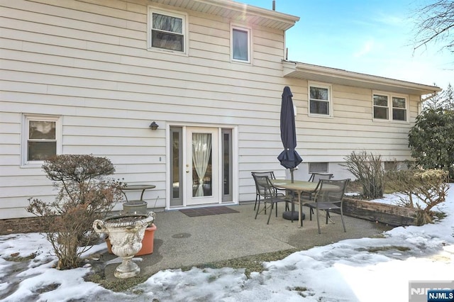 snow covered rear of property featuring a patio