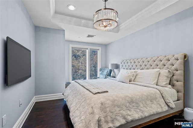 bedroom with an inviting chandelier, dark hardwood / wood-style flooring, and a tray ceiling