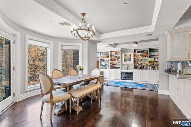 dining space with dark hardwood / wood-style floors, sink, a chandelier, a tray ceiling, and crown molding