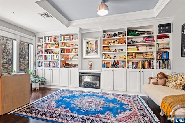 living area with a raised ceiling, ornamental molding, and dark hardwood / wood-style floors