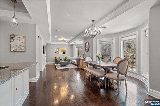 dining space featuring a chandelier, dark hardwood / wood-style flooring, and a tray ceiling