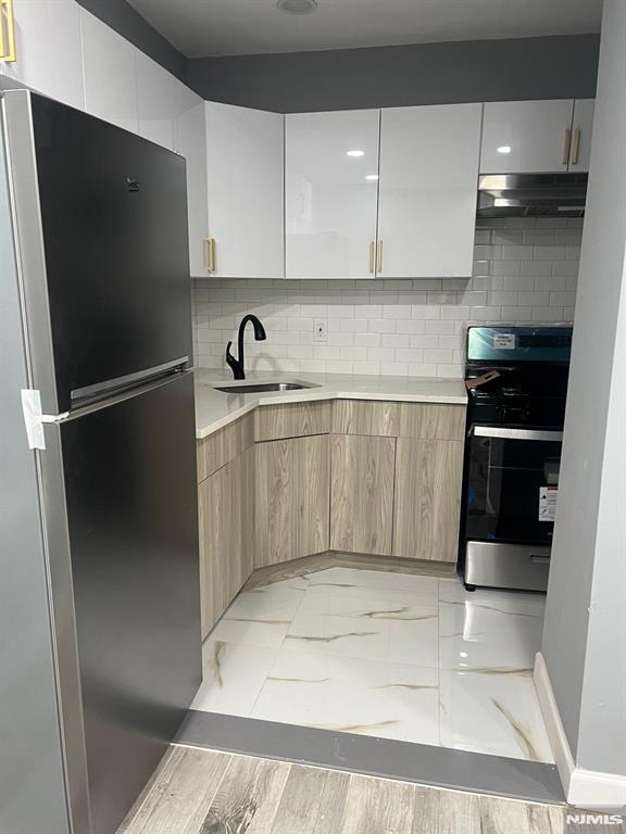 kitchen with white cabinetry, appliances with stainless steel finishes, sink, and light brown cabinetry