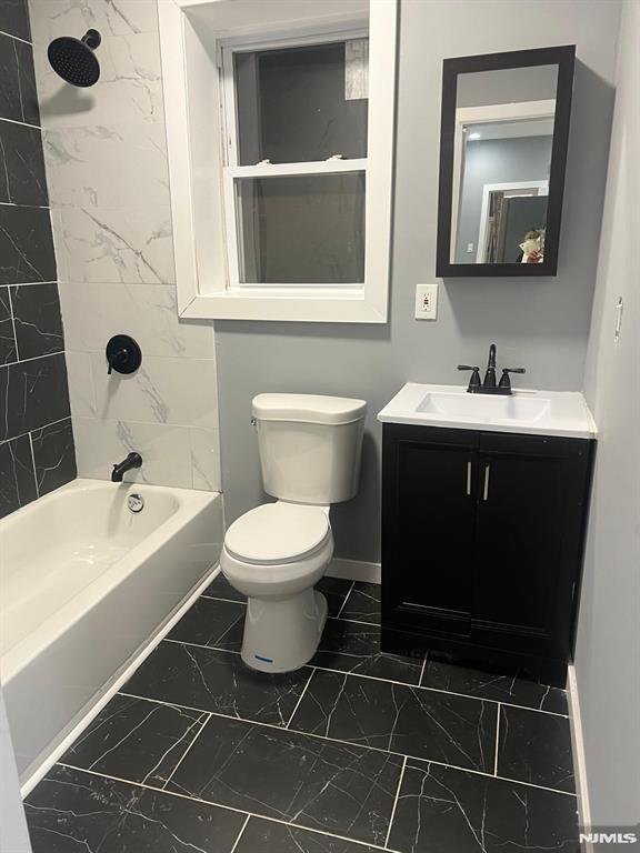 full bathroom with tiled shower / bath combo, vanity, and toilet