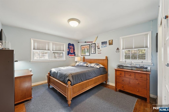 bedroom with multiple windows and dark hardwood / wood-style flooring