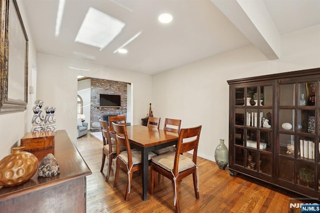 dining area featuring hardwood / wood-style flooring and a brick fireplace