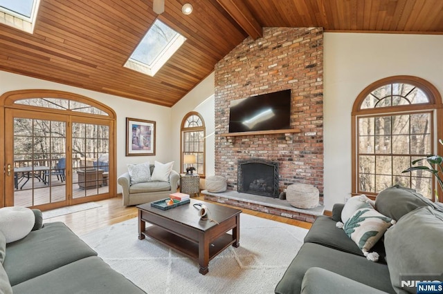 living room with a brick fireplace, light hardwood / wood-style flooring, wooden ceiling, and a skylight