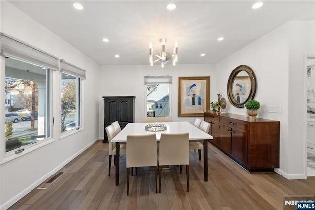 dining space featuring a healthy amount of sunlight, light hardwood / wood-style flooring, and a notable chandelier