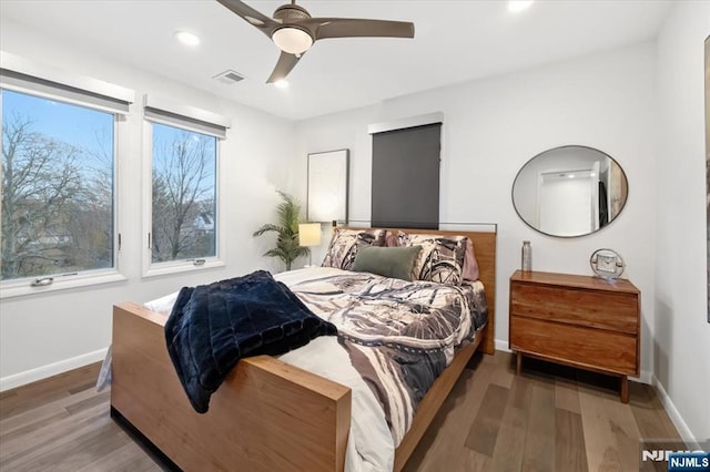 bedroom with multiple windows, wood-type flooring, and ceiling fan