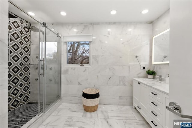 bathroom with walk in shower, vanity, and tile walls