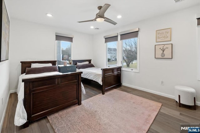 bedroom with multiple windows, dark wood-type flooring, and ceiling fan