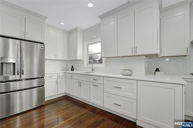 kitchen featuring stainless steel refrigerator with ice dispenser, sink, white cabinets, and decorative backsplash