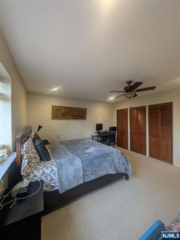 carpeted bedroom with multiple closets and ceiling fan