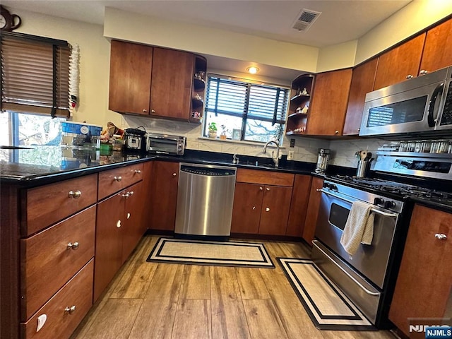 kitchen with backsplash, appliances with stainless steel finishes, sink, and light wood-type flooring