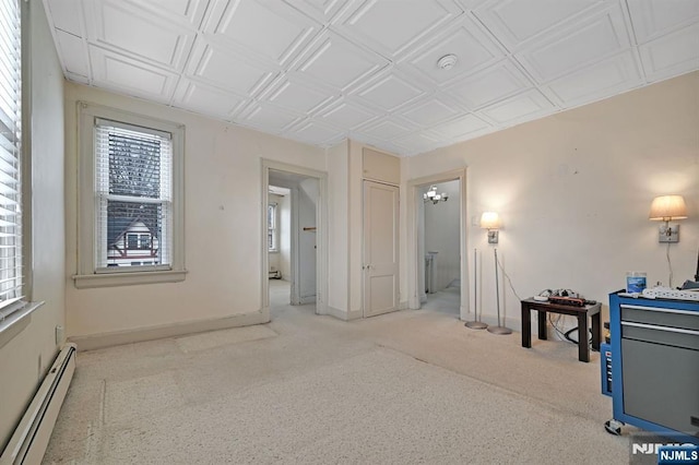 empty room featuring light carpet, baseboard heating, an ornate ceiling, and baseboards