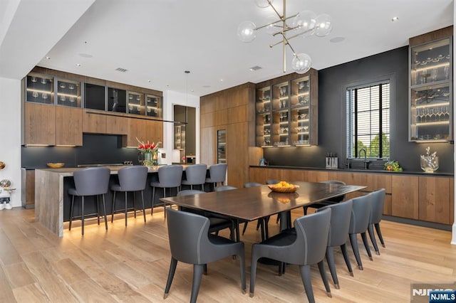 dining area featuring a chandelier, sink, and light hardwood / wood-style flooring