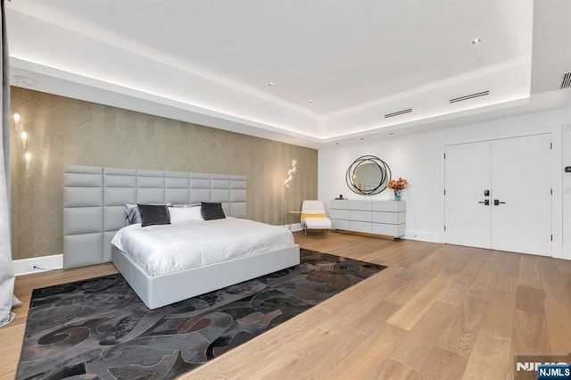 bedroom with a tray ceiling and hardwood / wood-style flooring