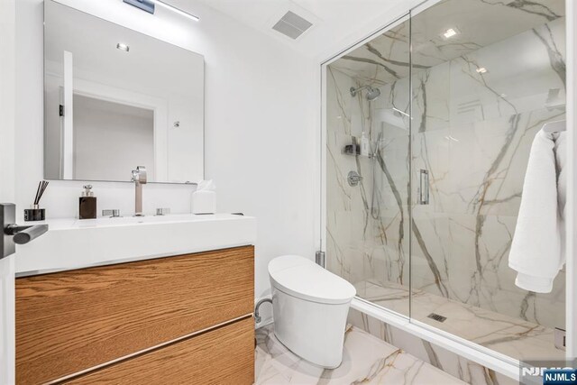 bathroom featuring vanity, toilet, and a shower with shower door