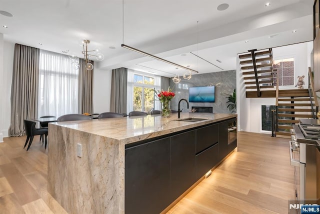 kitchen featuring a spacious island, stainless steel stove, sink, and light hardwood / wood-style flooring