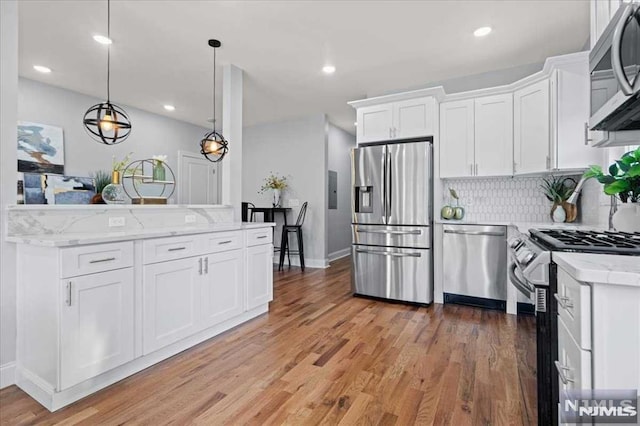 kitchen with stainless steel appliances, white cabinetry, hardwood / wood-style floors, and pendant lighting