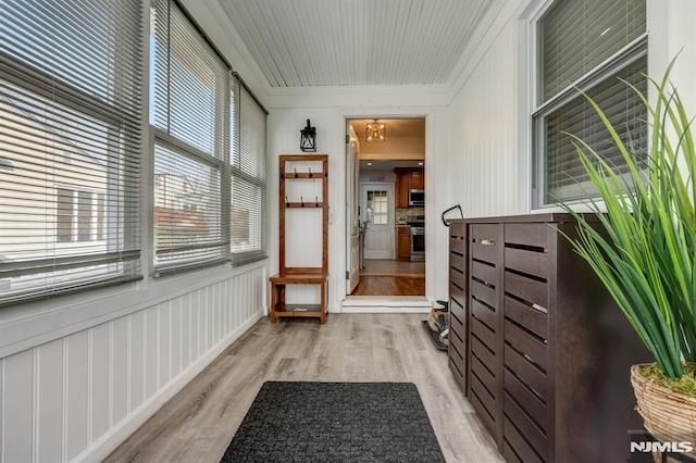 doorway with crown molding and light hardwood / wood-style floors