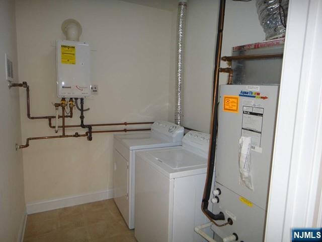 laundry room featuring water heater, washer and dryer, and tankless water heater