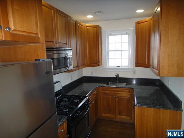 kitchen with appliances with stainless steel finishes, sink, and dark stone counters