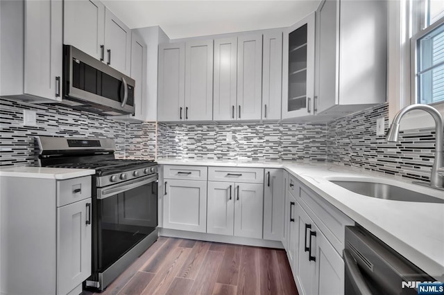 kitchen featuring sink, tasteful backsplash, dark hardwood / wood-style floors, stainless steel appliances, and light stone countertops