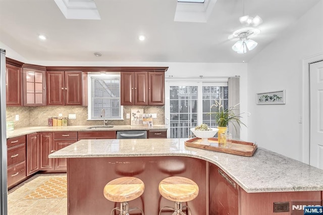 kitchen with stainless steel dishwasher, a kitchen breakfast bar, sink, and decorative backsplash