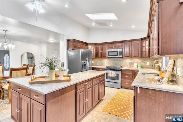 kitchen with a kitchen island, decorative light fixtures, sink, backsplash, and stainless steel appliances