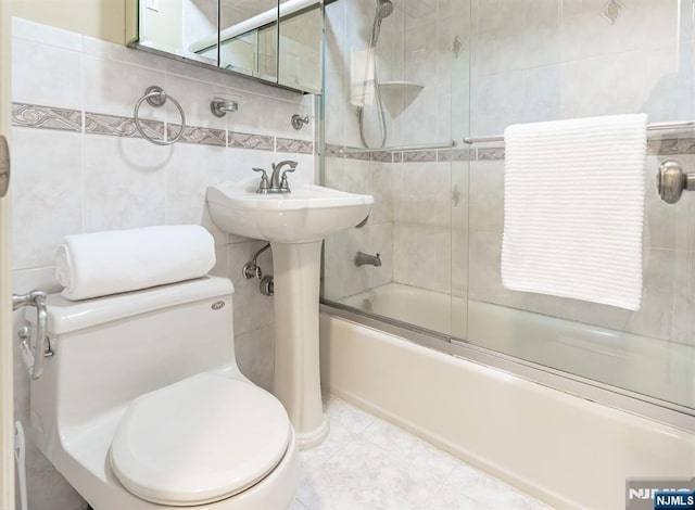 bathroom with enclosed tub / shower combo, toilet, and tile walls