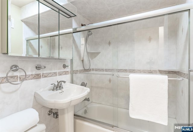 bathroom with bath / shower combo with glass door, tile walls, and backsplash