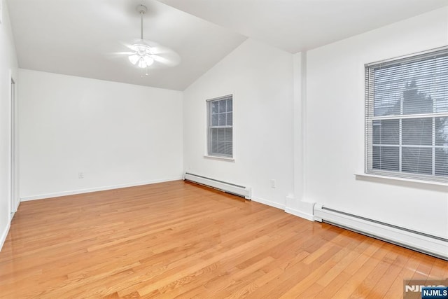 empty room with lofted ceiling, a baseboard heating unit, light hardwood / wood-style flooring, and ceiling fan