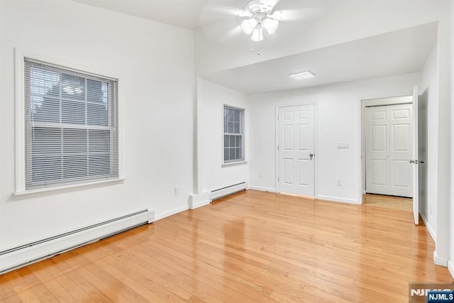 unfurnished room featuring ceiling fan, baseboard heating, and light hardwood / wood-style floors