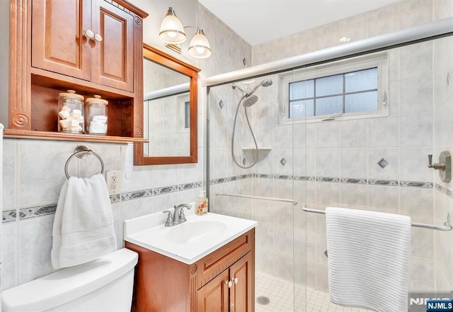 bathroom with vanity, toilet, tile walls, and walk in shower